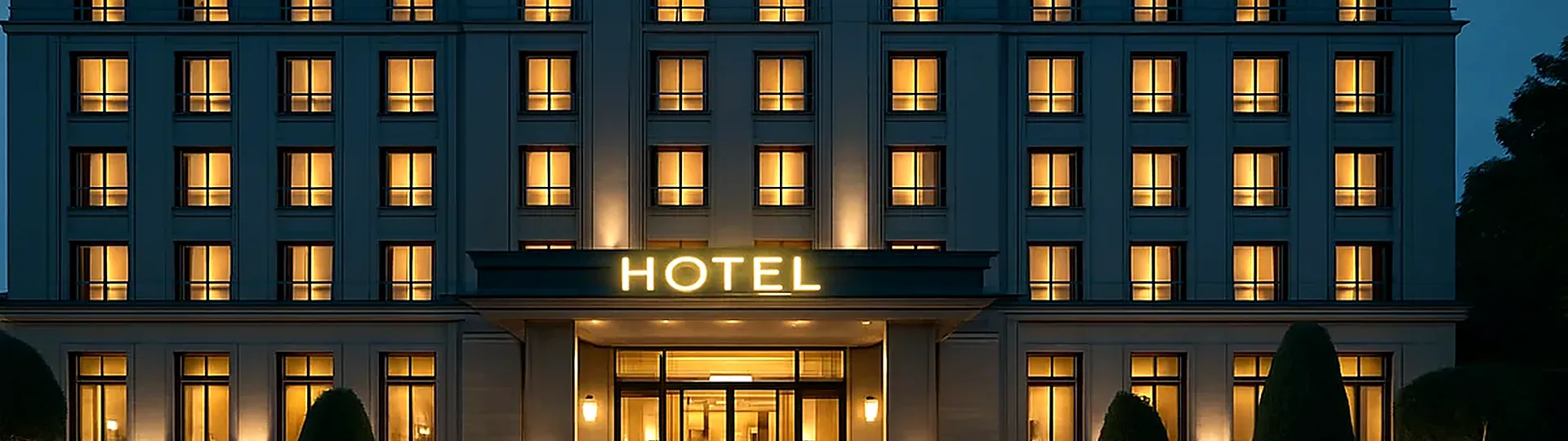 Elegant five-star hotel exterior at twilight with illuminated signage and manicured entrance